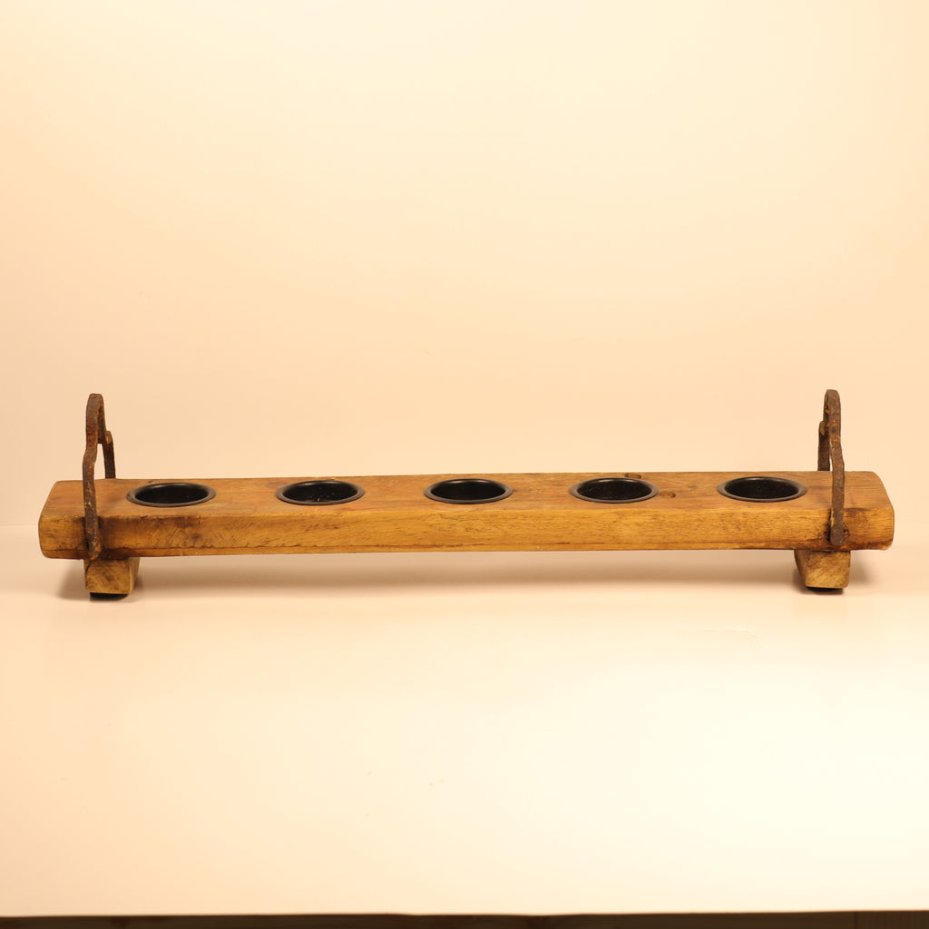 Wooden holder with five circular indentations on a beige background