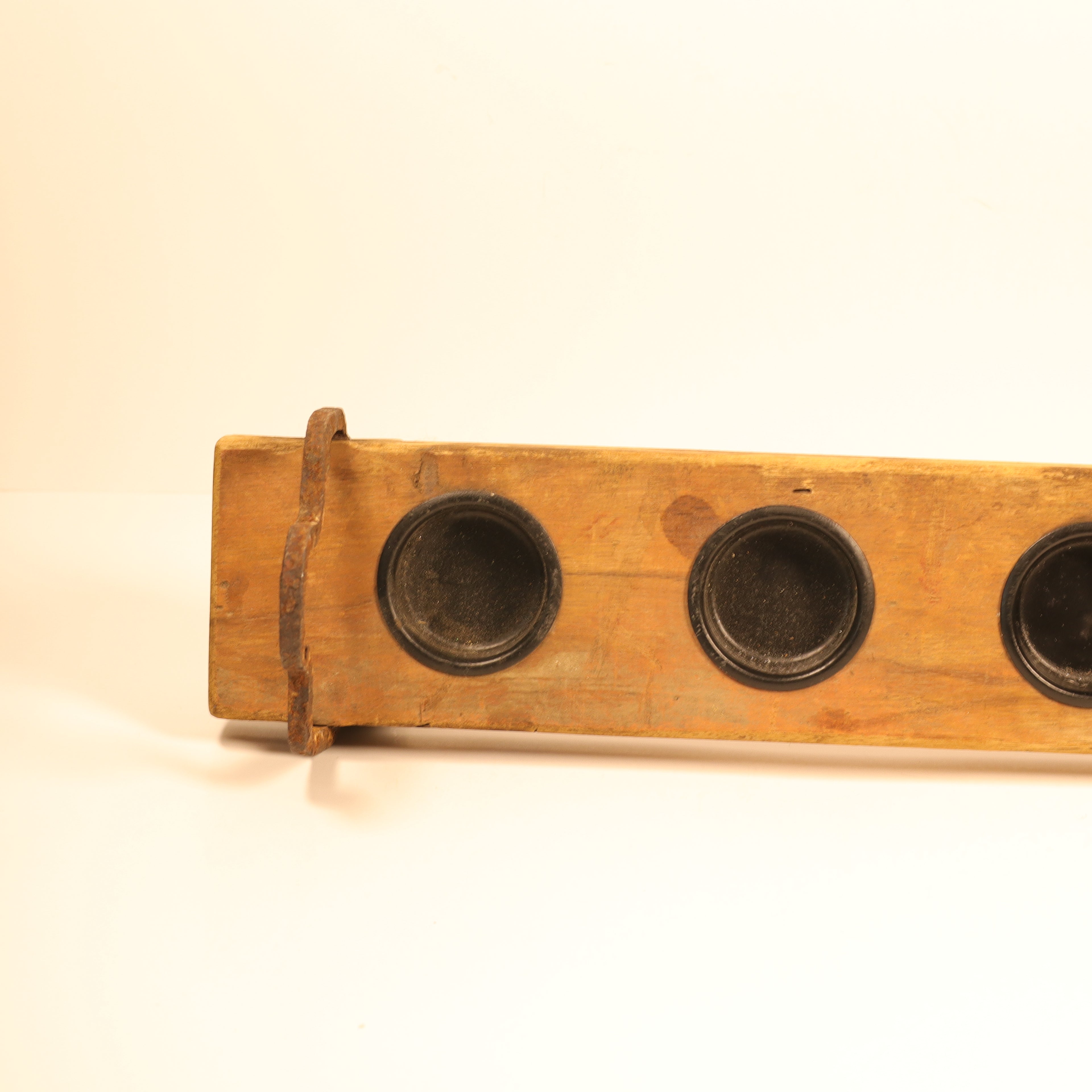 Wooden tool with three circular metal components on a beige background