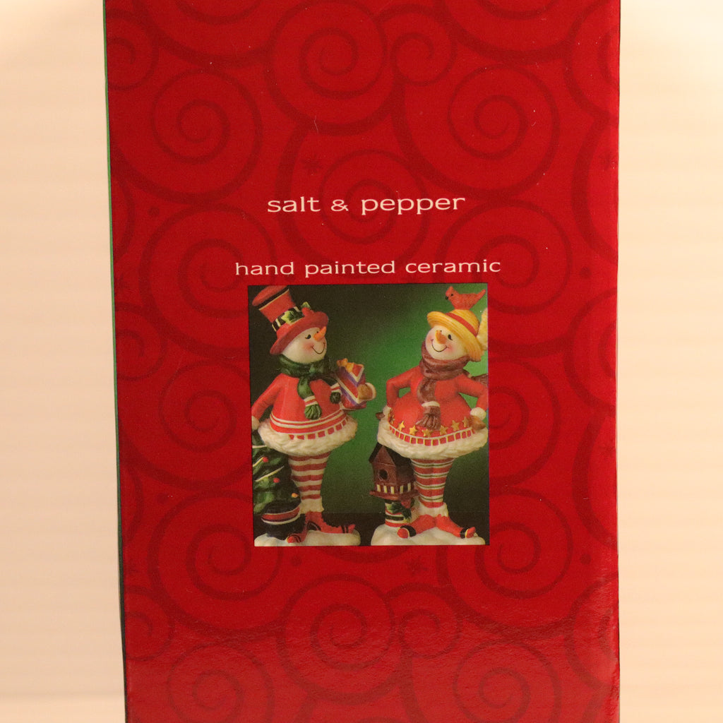 Red box with spiral pattern containing hand-painted ceramic snowmen on a beige background