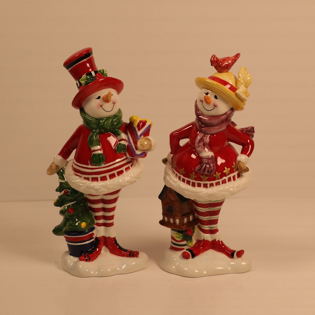 Two ceramic snowman figurines with festive attire on a beige background