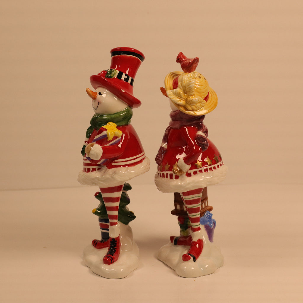 Two ceramic figures of a snowman and a woman in a red dress on a beige background