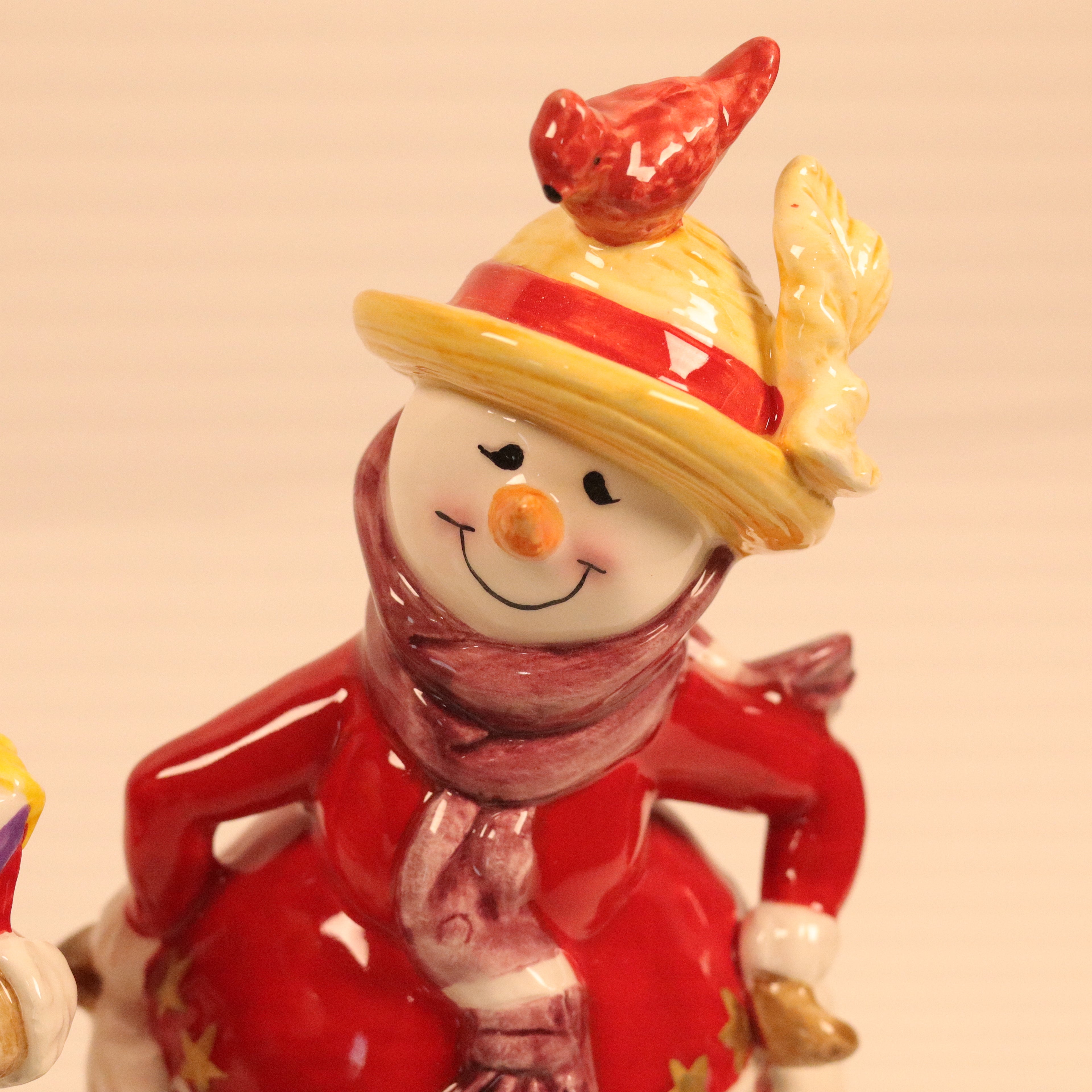 Decorative figurine of a snowman with a red hat and scarf on a beige background