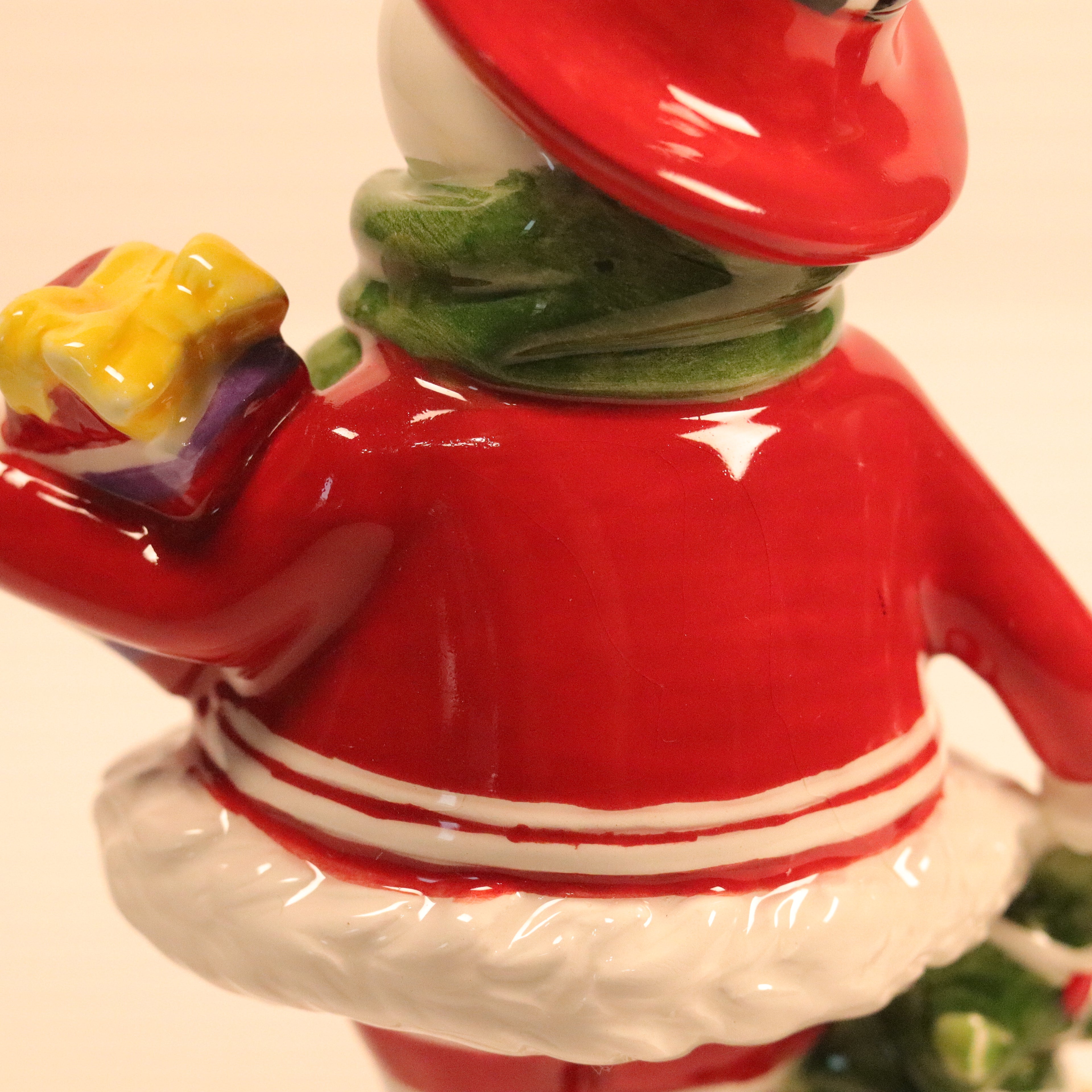 Decorative figurine of a character in a red outfit with a white hat and striped shirt, holding a yellow object.