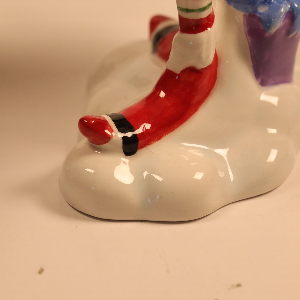 Close-up of a ceramic elf figurine with red shoes on a beige background