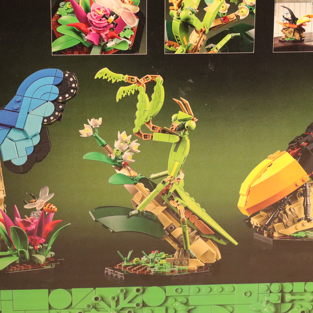 Toy figure of a green insect-like creature on a green base with other toy figures in the background.