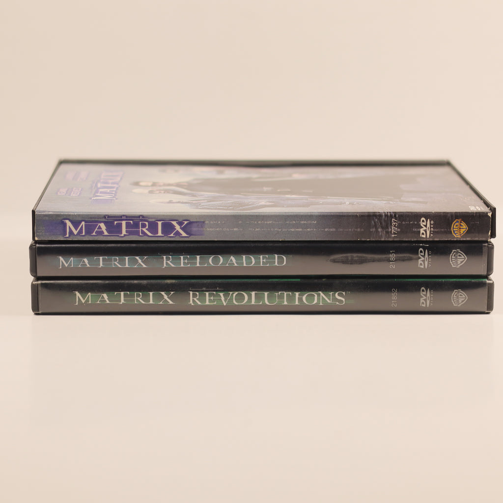 Three DVDs titled 'Matrix', 'Matrix Reloaded', and 'Matrix Revolutions' stacked on a beige background.